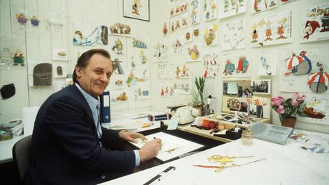 Albert Uderzo sitzt an seinem Schreibtisch und zeichnet, auf dem Tisch einige unfertige Zeichnungen, in den Idefix-Zeichentrick-Studios Paris 1986.