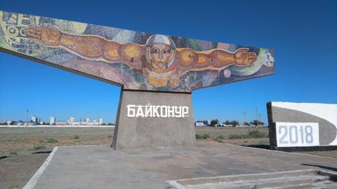 Das Monument "Der Fischer" am Eingang von Baikonur zeigt einen Mann mit ausgebreiteten Armen und Helm, der scheinbar im Weltraum schwebt,