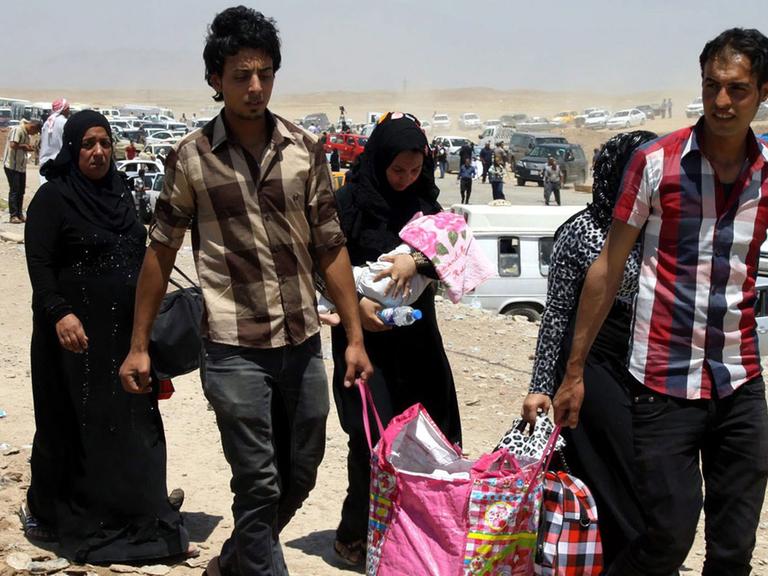 Eine sechsköpfige irakische Familie auf der Flucht vor der Gewalt in Mossul kommt mit einer Tragetasche an einem Checkpoint in Erbil im Nordirak an.