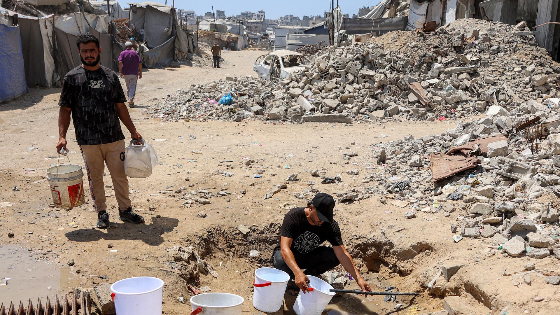 Ein Mann füllt Eimer mit Wasser, das aus den Restbeständen unterirdischer Leitungen in einem Lager für Kriegsvertriebene im Stadtviertel Sheikh Radwan in Gaza-Stadt geschöpft wird (06.07.2026) Ein Mann füllt Eimer mit Wasser, das aus den Restbeständen unterirdischer Leitungen in einem Lager für Kriegsvertriebene im Stadtviertel Sheikh Radwan in Gaza-Stadt geschöpft wird (06.07.2026)