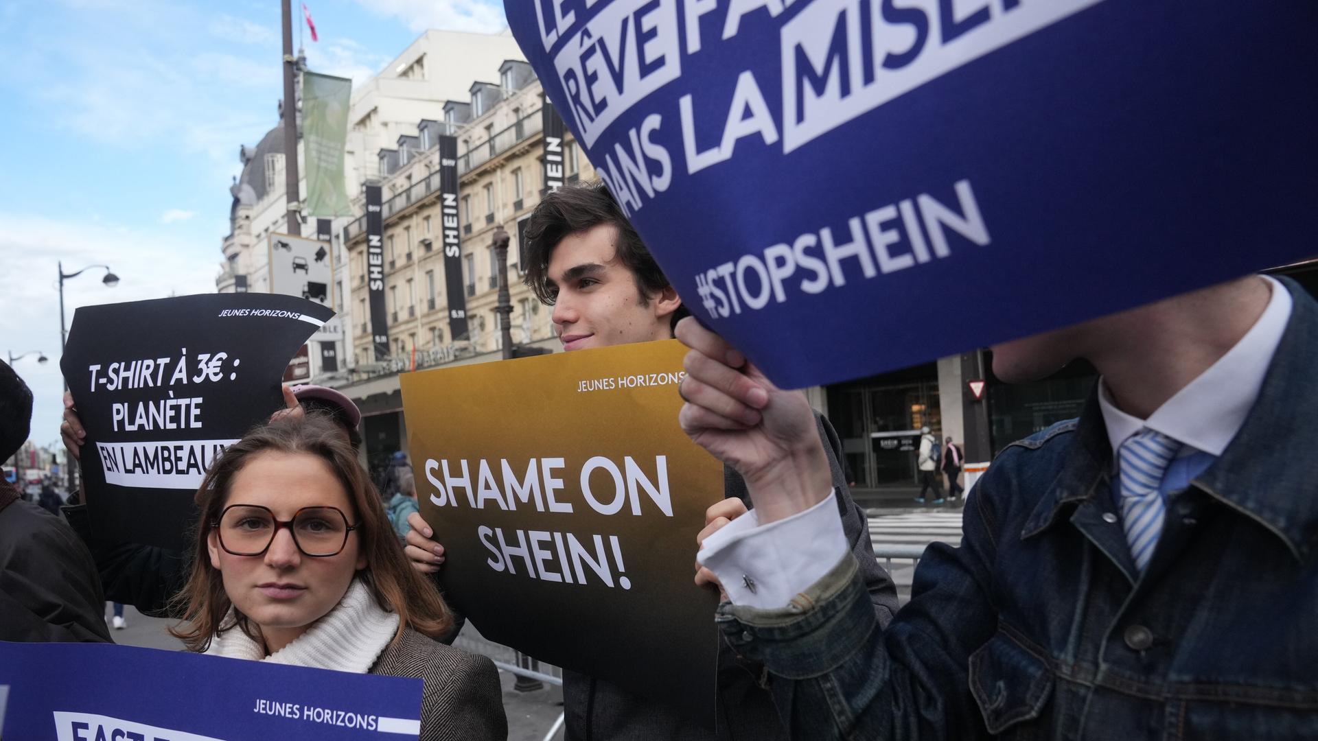 Demonstranten halten Plakate vor dem Kaufhaus BHV in Paris, wo der Fast-Fashion-Gigant Shein am 5. November 2025 seine erste permanente Filiale eröffnet hat. Demonstranten halten Plakate vor dem Kaufhaus BHV in Paris, wo der Fast-Fashion-Gigant Shein am 5. November 2025 seine erste permanente Filiale eröffnet hat.