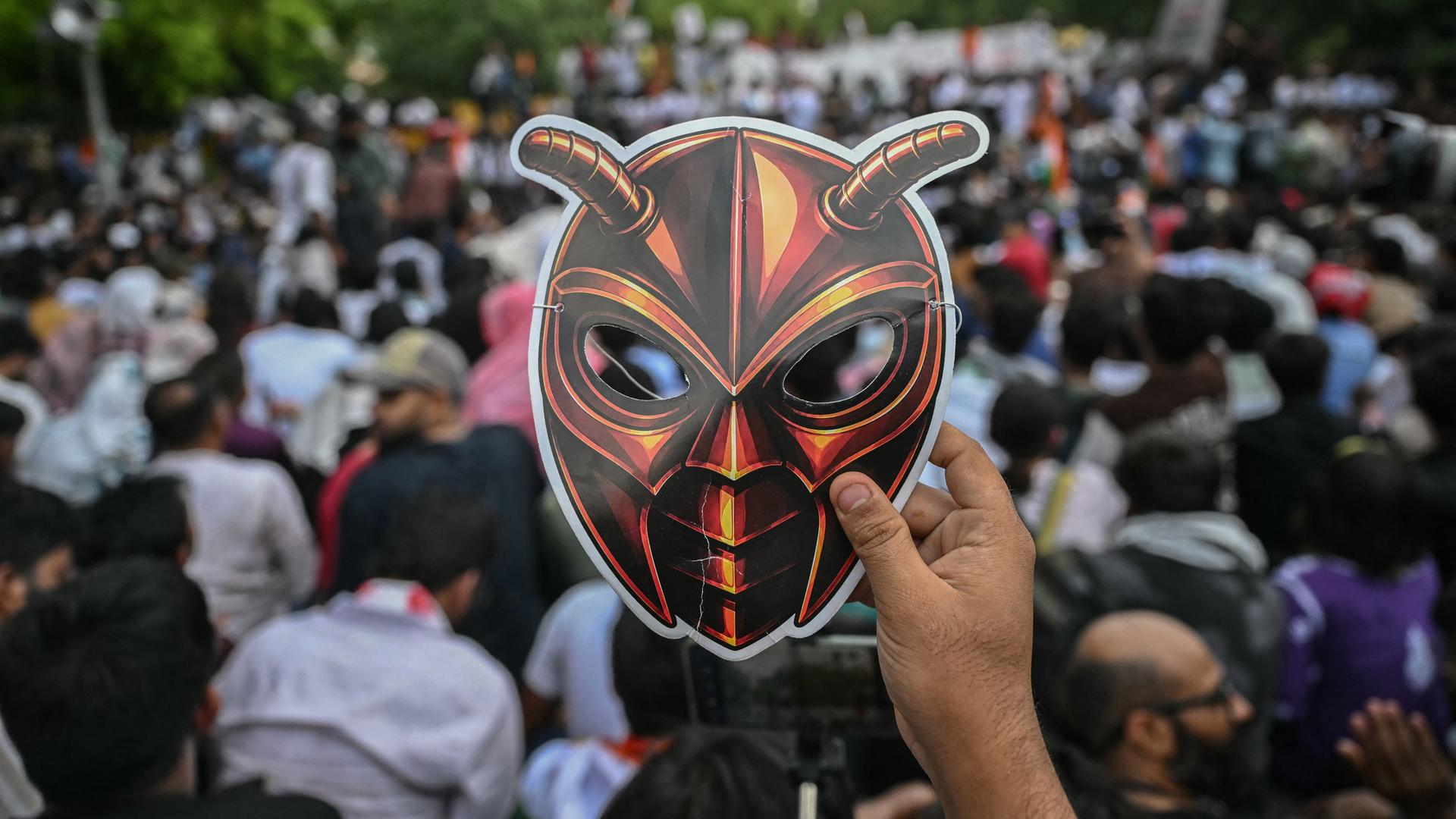 Ein Unterstützer der Cockroach Janta Party (CJP) hält während eines Protests in New Delhi am 6. Juni 2026 eine Maske in Kamera