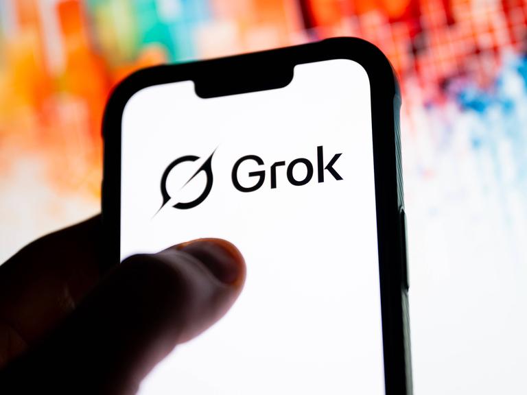 Daumen auf Smartphone-Screen, auf dem "Grok" steht