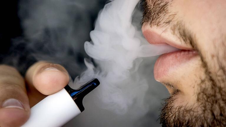 Ein Mann raucht eine Einweg-E-Zigarette