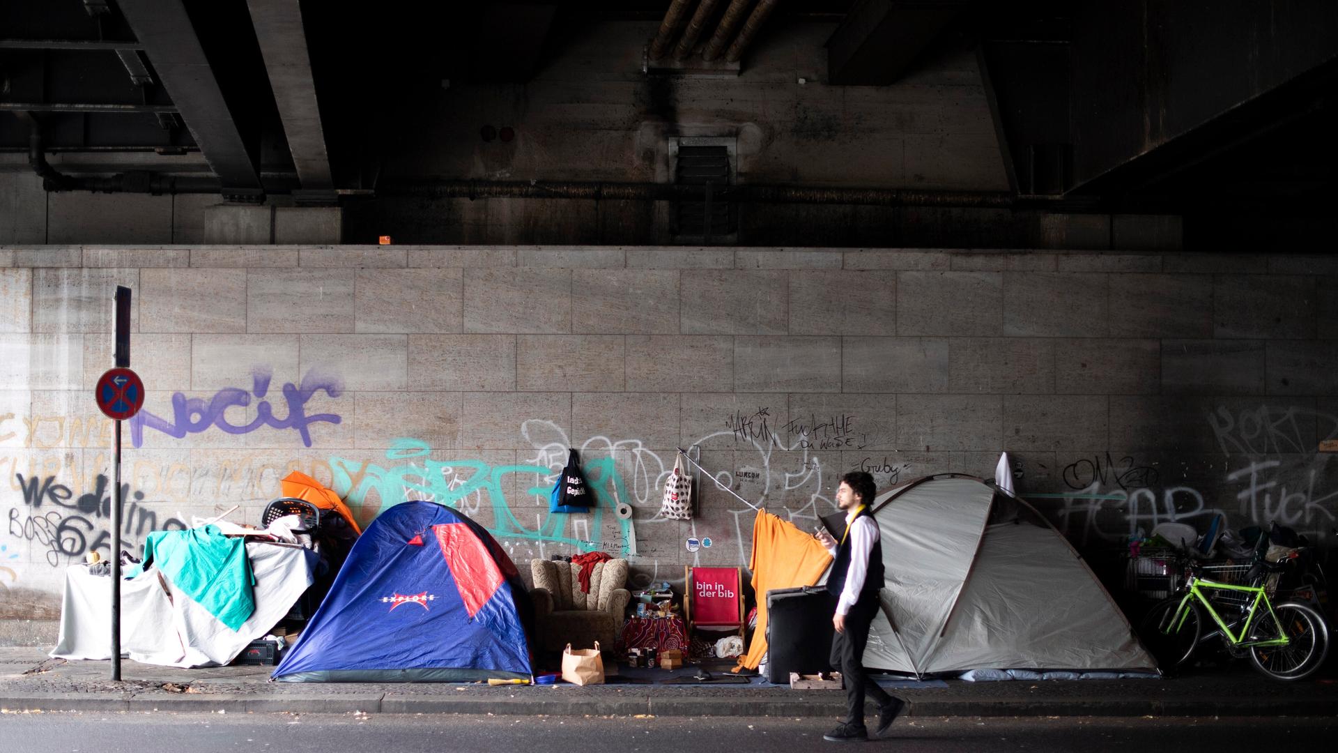 Ein Mann geht in einer Unterführung  an mehreren Zelten vorbei (25.08.2022)