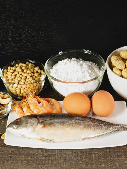 Zu den Hauptallergenen zählen: Fisch, Erdnüsse, Mandeln, Milch, Weizenmehl, Soja, Eier, Cashewkerne und Meeresfrüchte. Hier auf einem rustikalen Tisch.