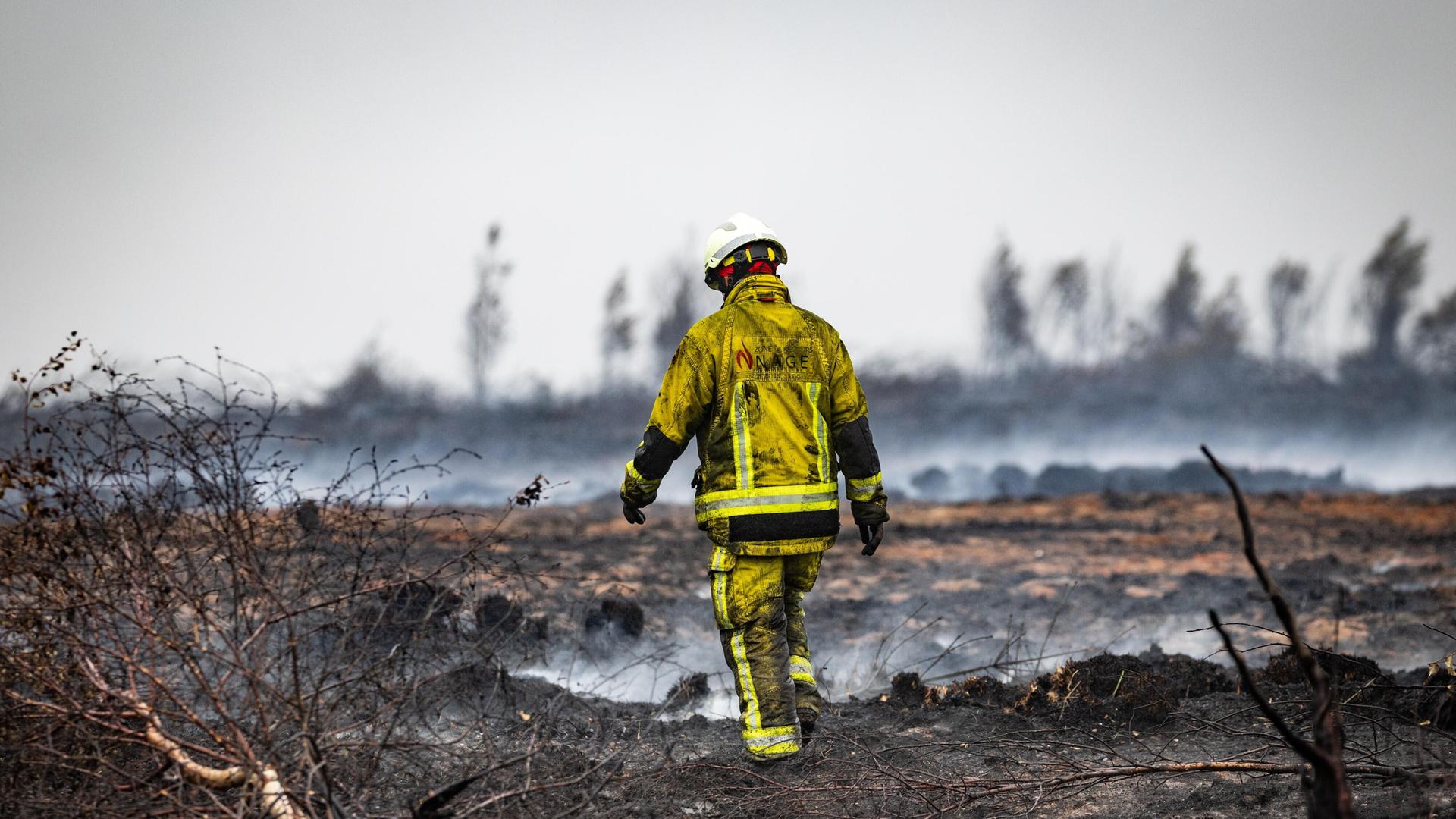 Ein Feuerwehrmann geht durch die abgebrannte Moorlandschaft im Hohen Venn.