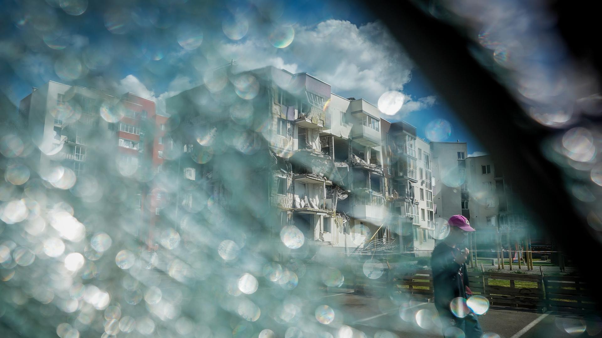 Durch eine zerbrochene Windschutzscheibe ist ein zerstörtes Wohnhaus in Butscha bei Kiew zu sehen.