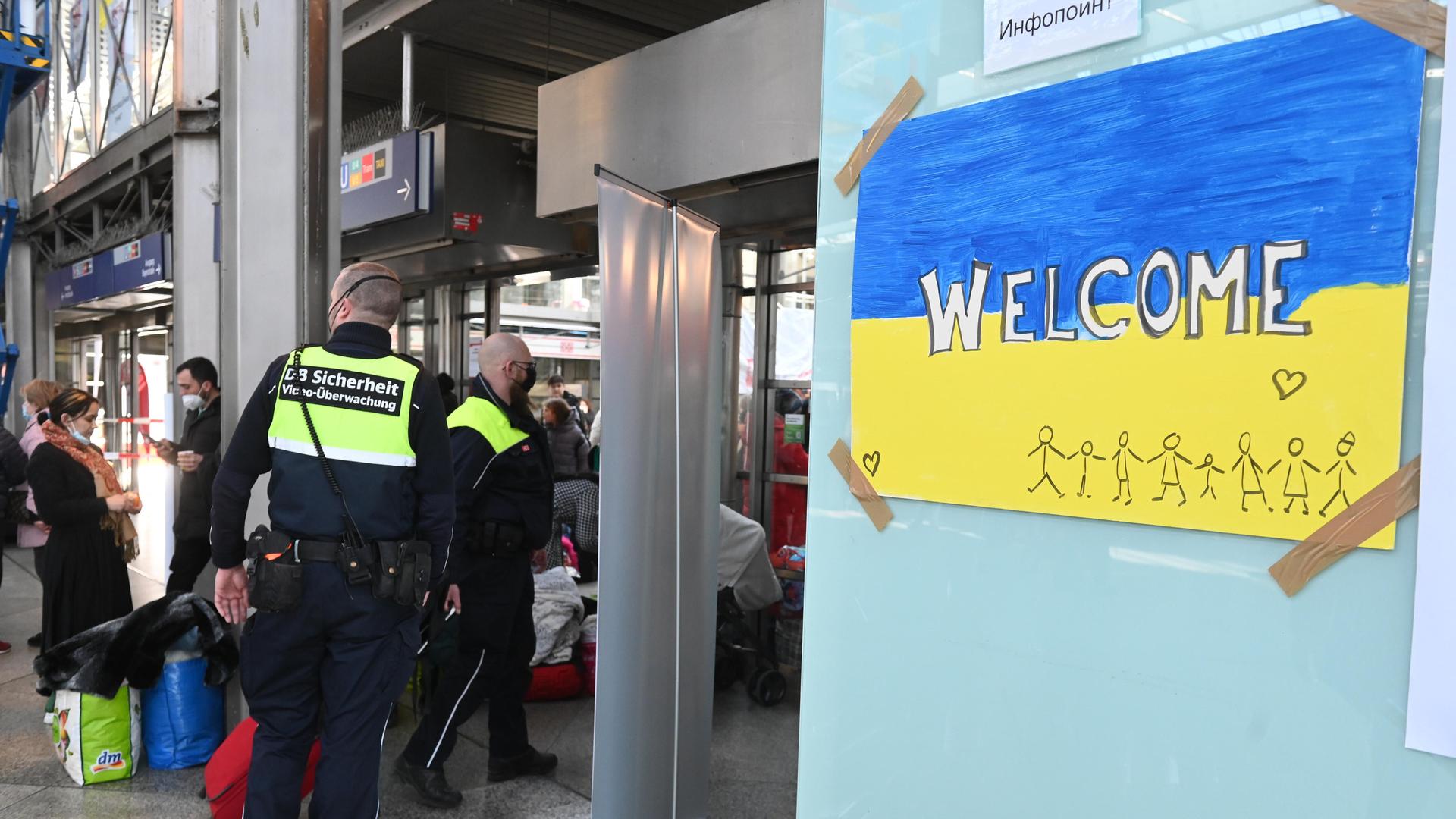 Mitarbeiter der DB-Sicherheit steht am Münchner Hauptbahnhof neben einem selbstgemalten Bild mit ukrainischer Flagge, der Aufschrift „welcome“ sowie Strichmännchen und einem Herzen (11.03.2022) Mitarbeiter der DB-Sicherheit steht am Münchner Hauptbahnhof neben einem selbstgemalten Bild mit ukrainischer Flagge, der Aufschrift „welcome“ sowie Strichmännchen und einem Herzen (11.03.2022)