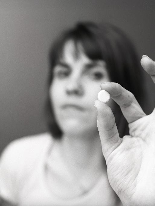 Eine Frau hält eine weiße Pille zwischen ihren Fingern. Eine Illustration für die Einnahme von Medikamenten oder für Antibabypillen zu dieser Zeit. Schweden 1971