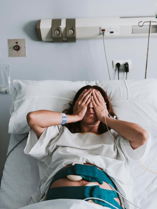 Eine schwangere Frau liegt in einem Krankenhausbett