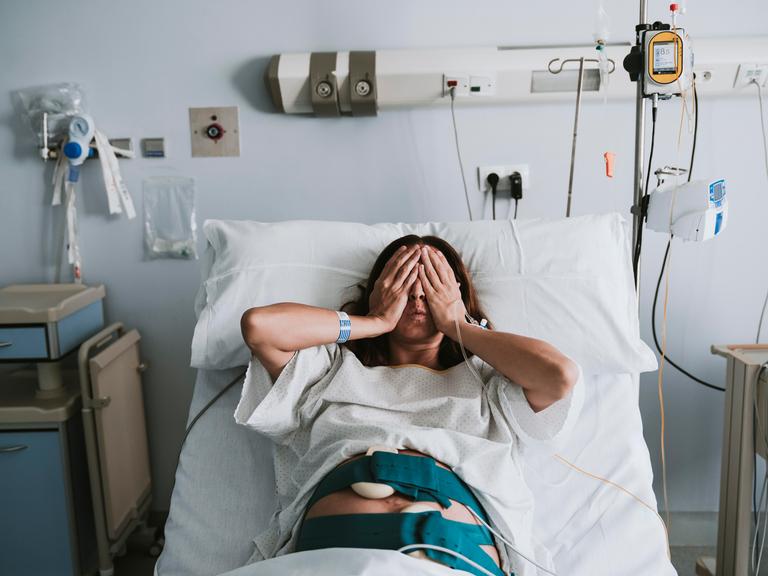 Eine schwangere Frau liegt in einem Krankenhausbett