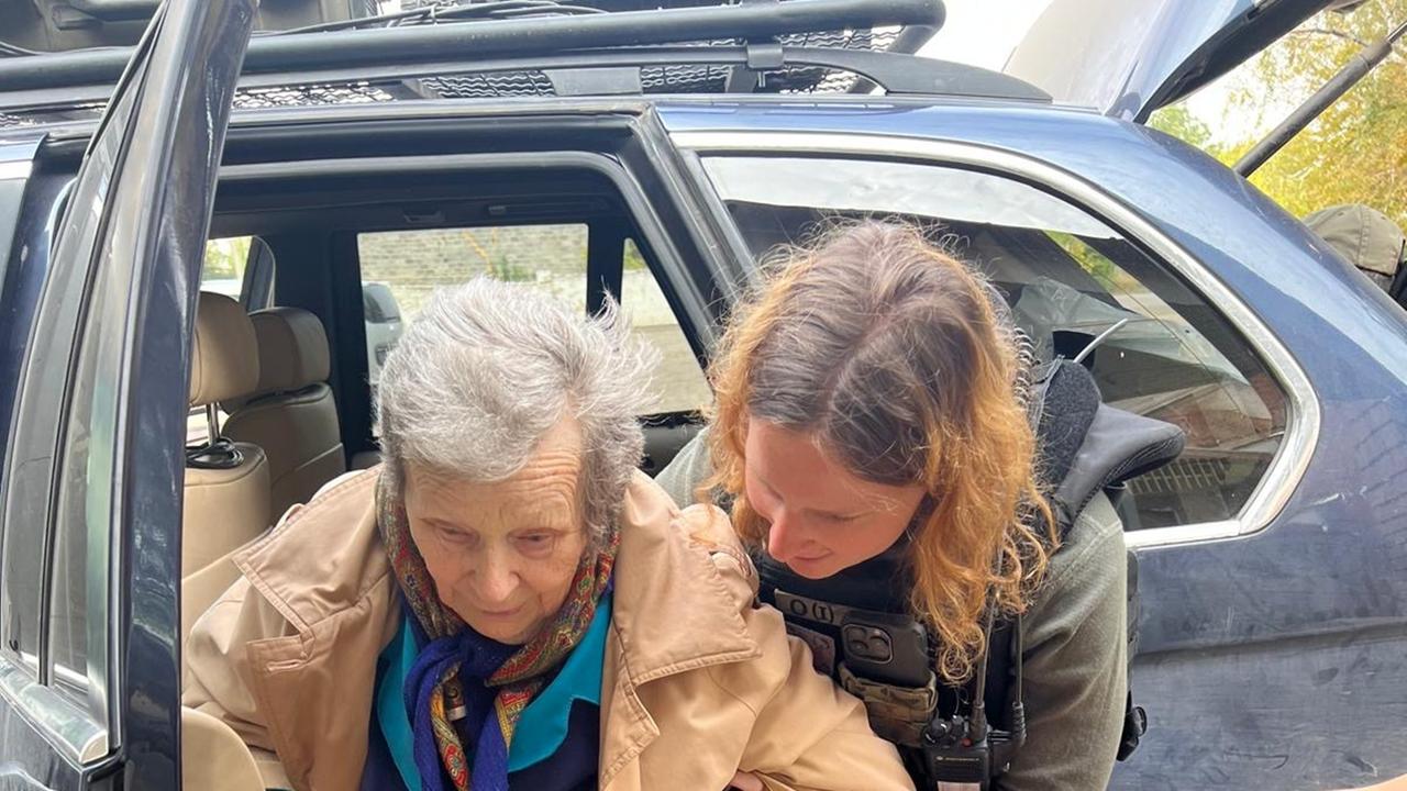 Anna Elsbernd hilft einer Frau mit Gehstock aus einem Auto zu steigen