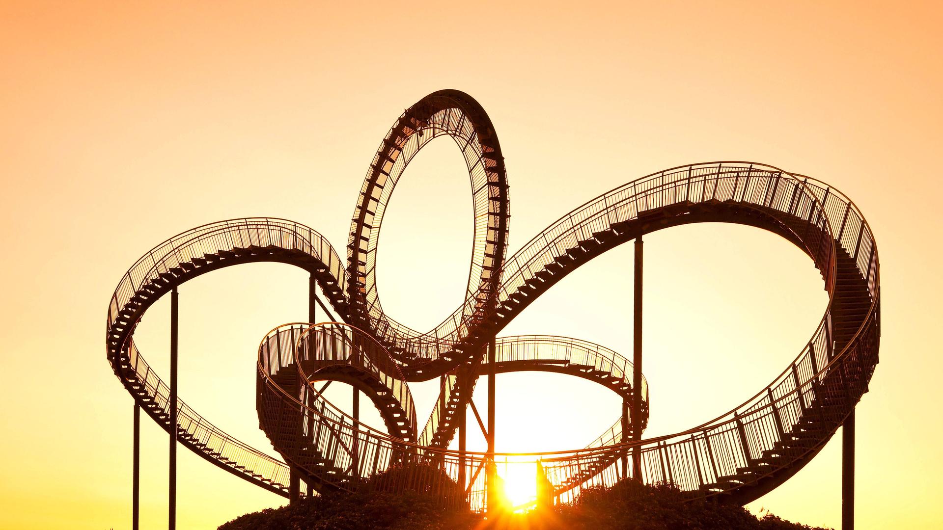 Die einer Achterbahn nachempfundene Großskulptur Tiger and Turtle vor einem Sonnenaufgang