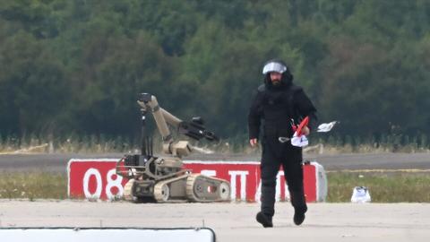 Ein Kriminaltechniker geht auf dem Flughafen Leipzig/Halle neben einem Sprengroboter, um die Drohne zu entschärfen.