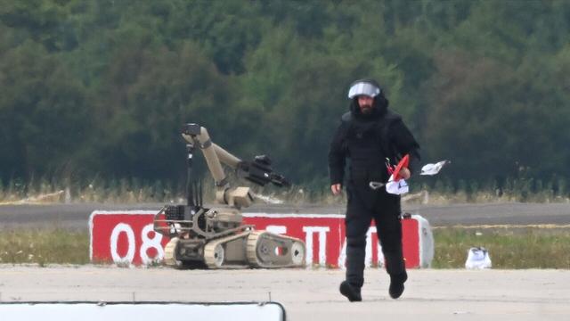 Ein Kriminaltechniker geht auf dem Flughafen Leipzig/Halle neben einem Sprengroboter, um die Drohne zu entschärfen.