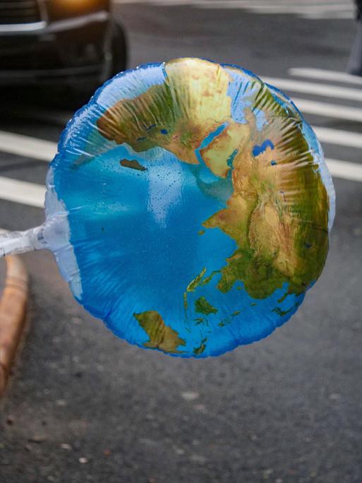 Ein Luftballon mit einer Weltkarte weht im Wind