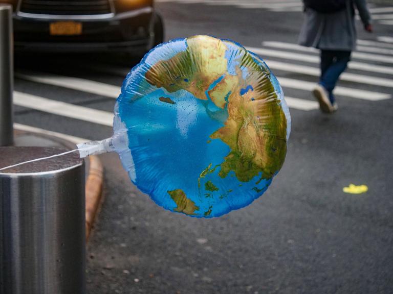 Ein Luftballon mit einer Weltkarte weht im Wind
