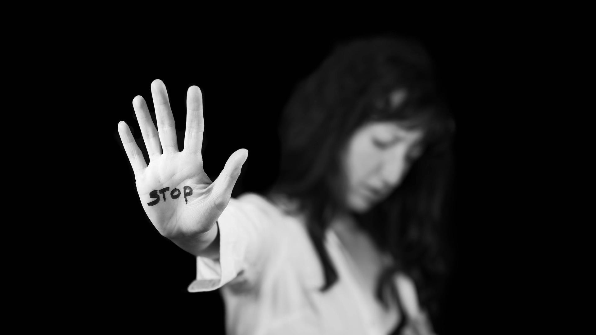 Frau streckt ihre Handfläche aus, auf der Stopp steht