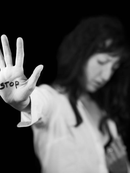 Frau streckt ihre Handfläche aus, auf der Stopp steht