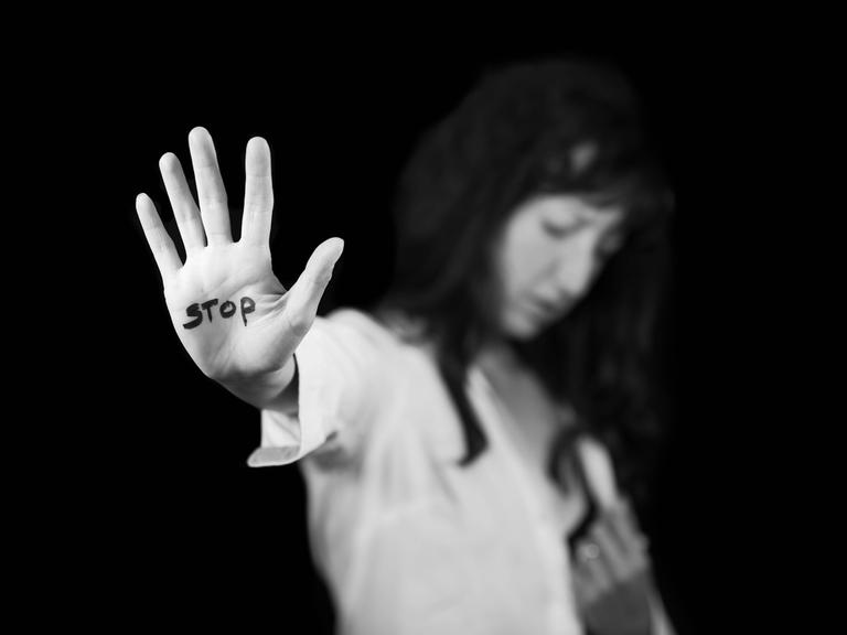 Frau streckt ihre Handfläche aus, auf der Stopp steht