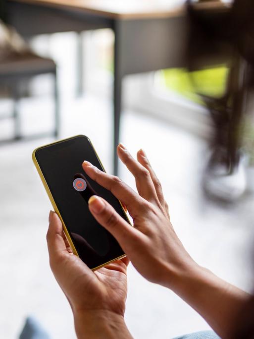 Eine Frau hält ein Handy in der Hand. Auf dem Handybildschirm wird die Möglichkeit angezeigt, das Handy auszuschalten.