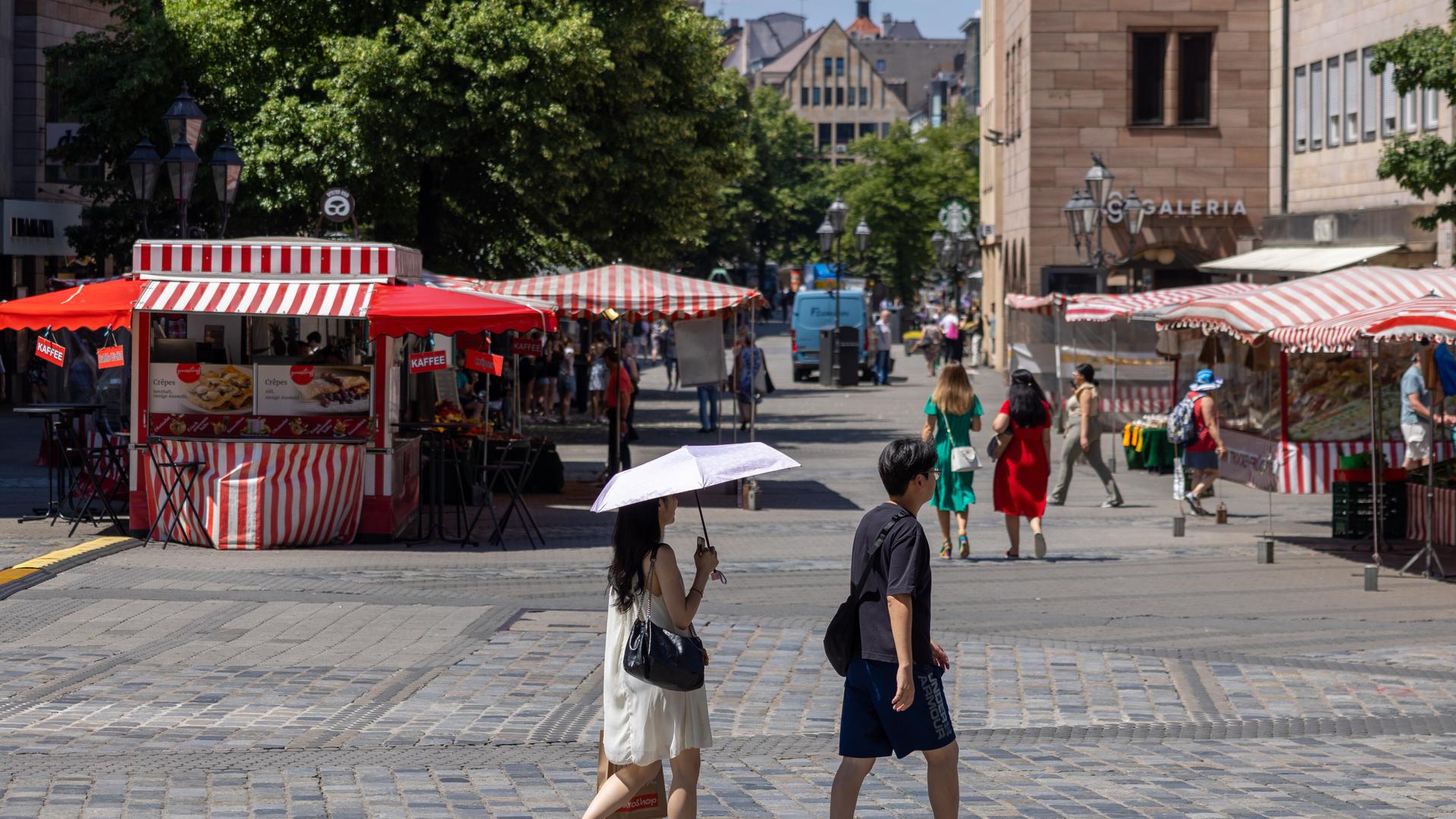 Die Fußgängerzone Nürnbergs an einem sonnigen Junitag. Menschen schützen sich mit Schirm und Hut. Die Fußgängerzone Nürnbergs an einem sonnigen Junitag. Menschen schützen sich mit Schirm und Hut.