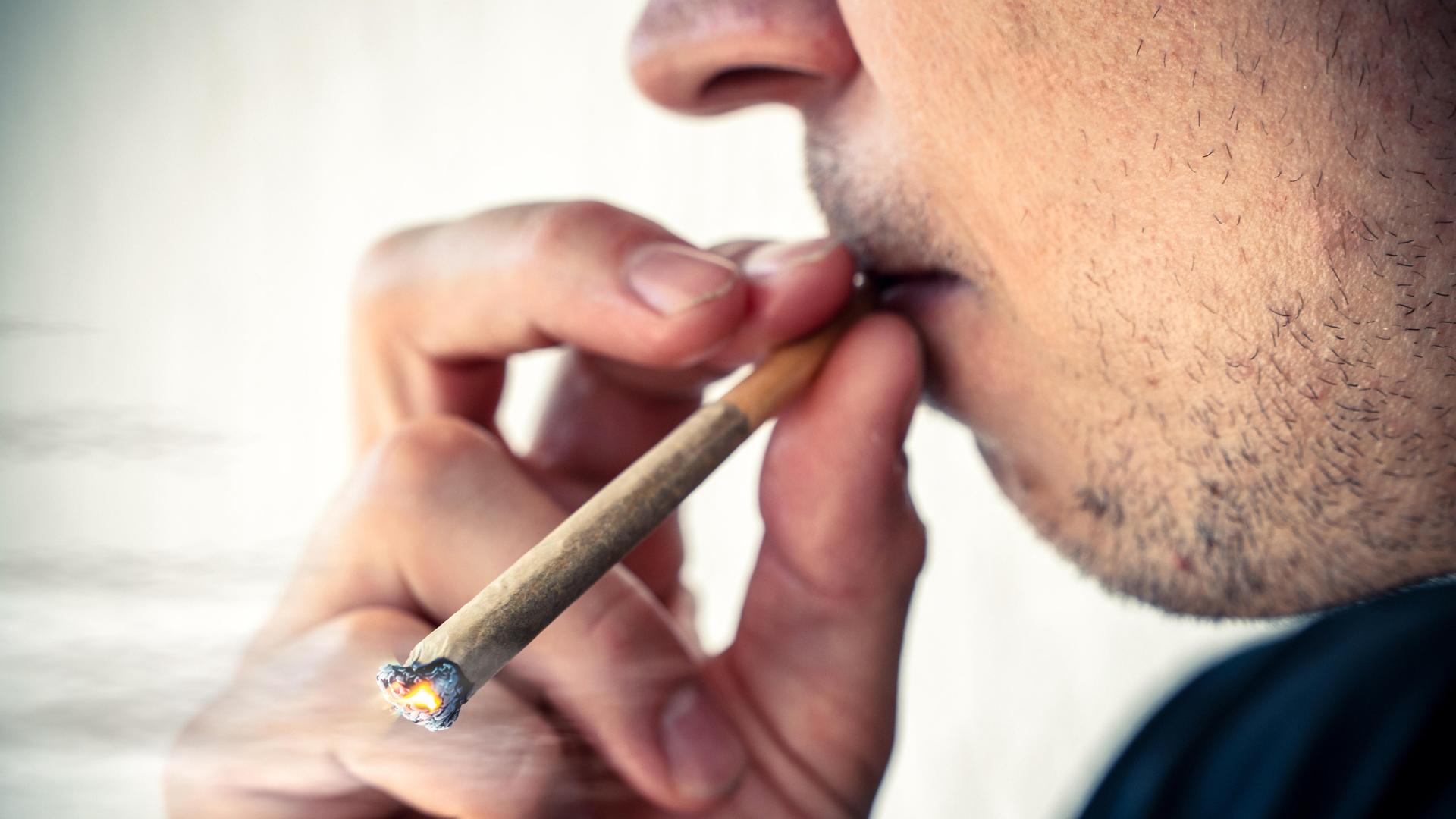Person kifft einen Joint aus Cannabis bzw. THC in der Öffentlichkeit.