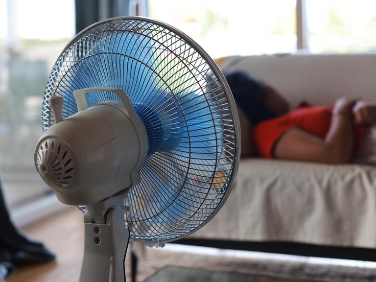 Eine Frau schläft, im Vordergrund ein Ventilator