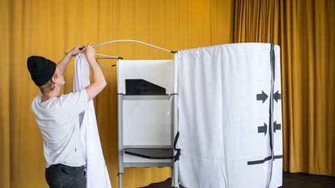 Ein Mann stellt im Rathaus von Reykjavík eine Wahlkabine auf (Island, 27.08. 2026)