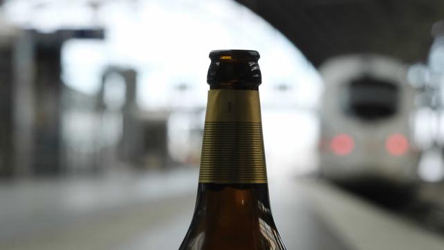 Eine leere Flasche Bier steht an einem Bahnsteig