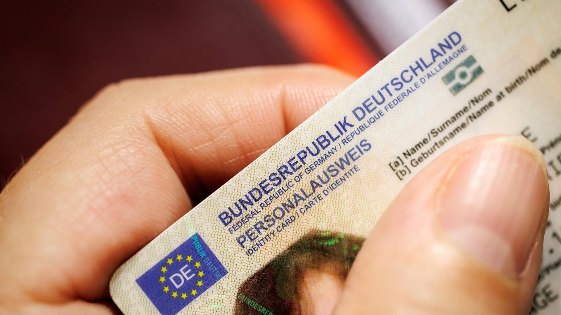 Eine Frau hält einen Personalausweis der Bundesrepublik Deutschland im Scheckkartenformat in ihrer Hand.