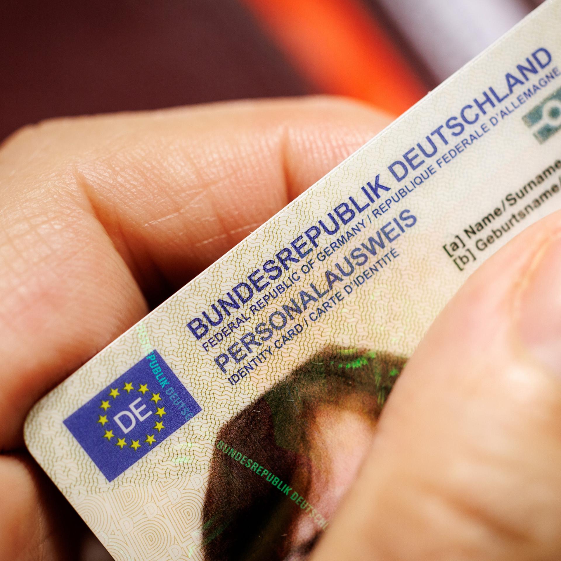 Eine Frau hält einen Personalausweis der Bundesrepublik Deutschland im Scheckkartenformat in ihrer Hand.