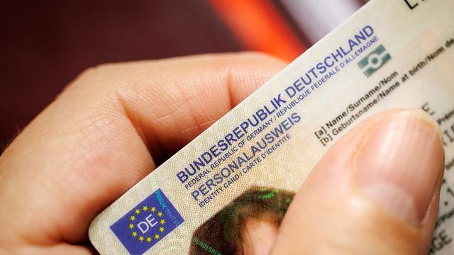 Eine Frau hält einen Personalausweis der Bundesrepublik Deutschland in ihrer Hand.