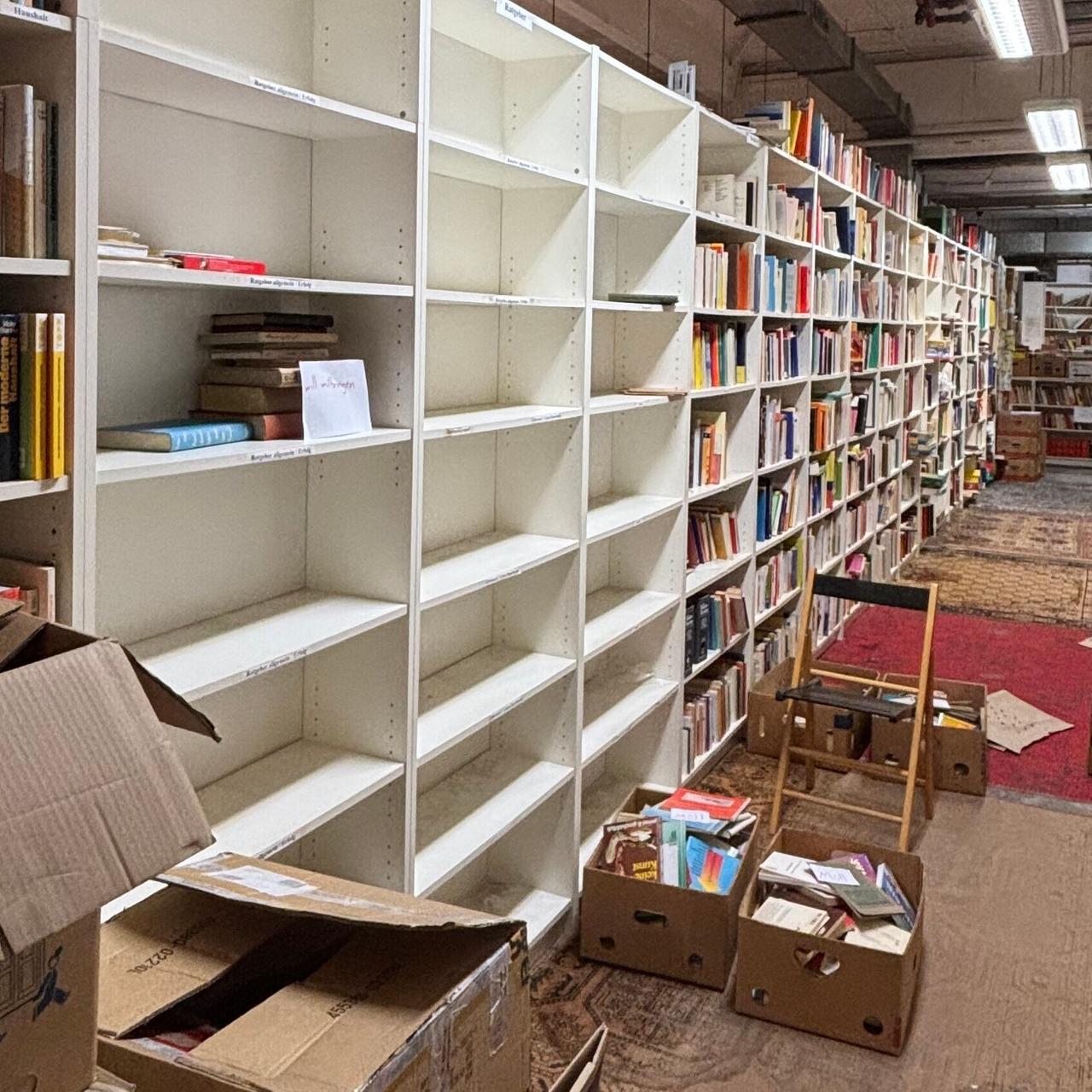 Für einen Umzug werden im Antiquariat reihenweise Regale voller Bücher leergeräumt.