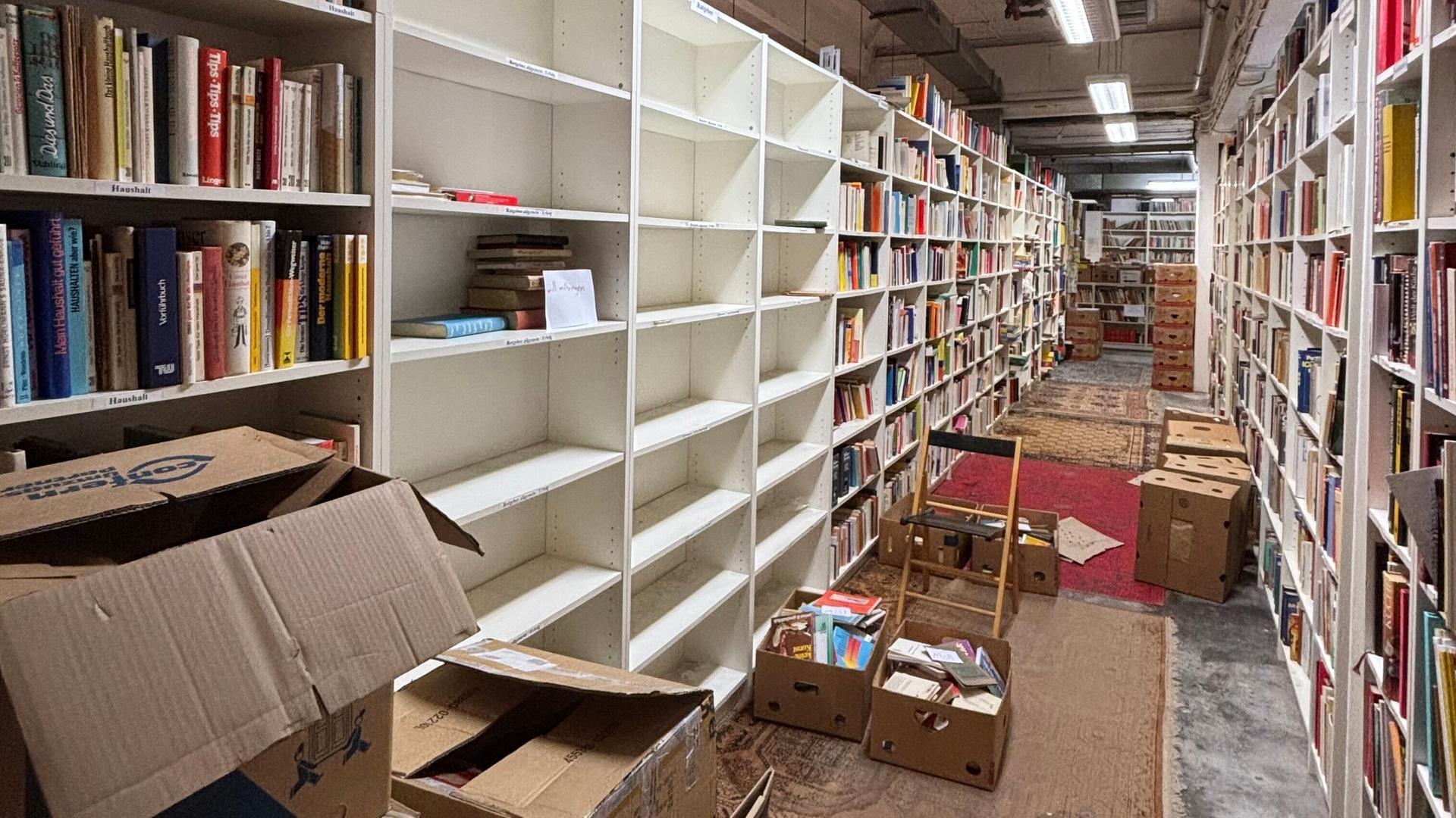 Für einen Umzug werden im Antiquariat reihenweise Regale voller Bücher leergeräumt.