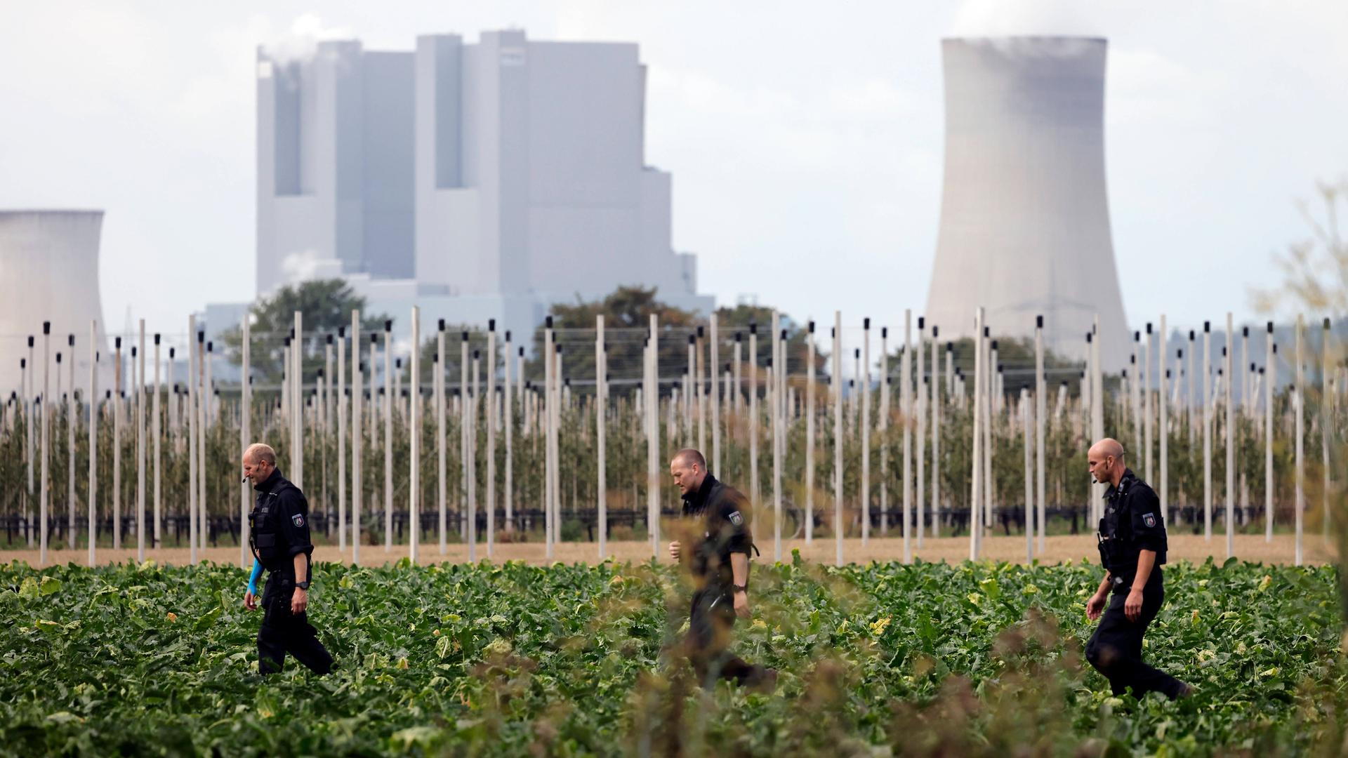Nahe einem mutmaßlichen Anschlag auf ein Umspannwerk nahe Bergheim bei Köln durchsuchen Polizisten umliegende Felder. Im Hintergrund ist ein Kraftwerk zu sehen. Nahe einem mutmaßlichen Anschlag auf ein Umspannwerk nahe Bergheim bei Köln durchsuchen Polizisten umliegende Felder. Im Hintergrund ist ein Kraftwerk zu sehen.