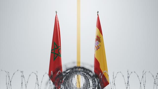 Die Flaggen von Marokko und Spanien, getrennt durch eine gelbe Linie hinter scharf gewundenem Stacheldraht vor weißem Hintergrund.