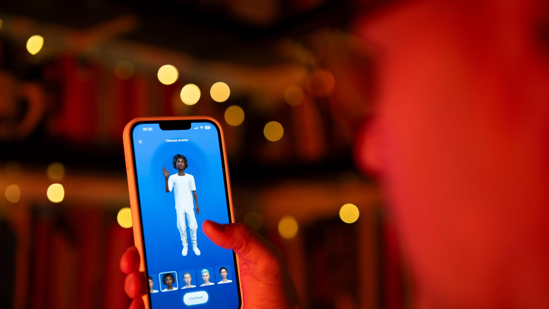 Ein Nutzer mit einem Handy. Auf dem Bildschirm ist eine Figur zu sehen. Ein Nutzer mit einem Handy. Auf dem Bildschirm ist eine Figur zu sehen.