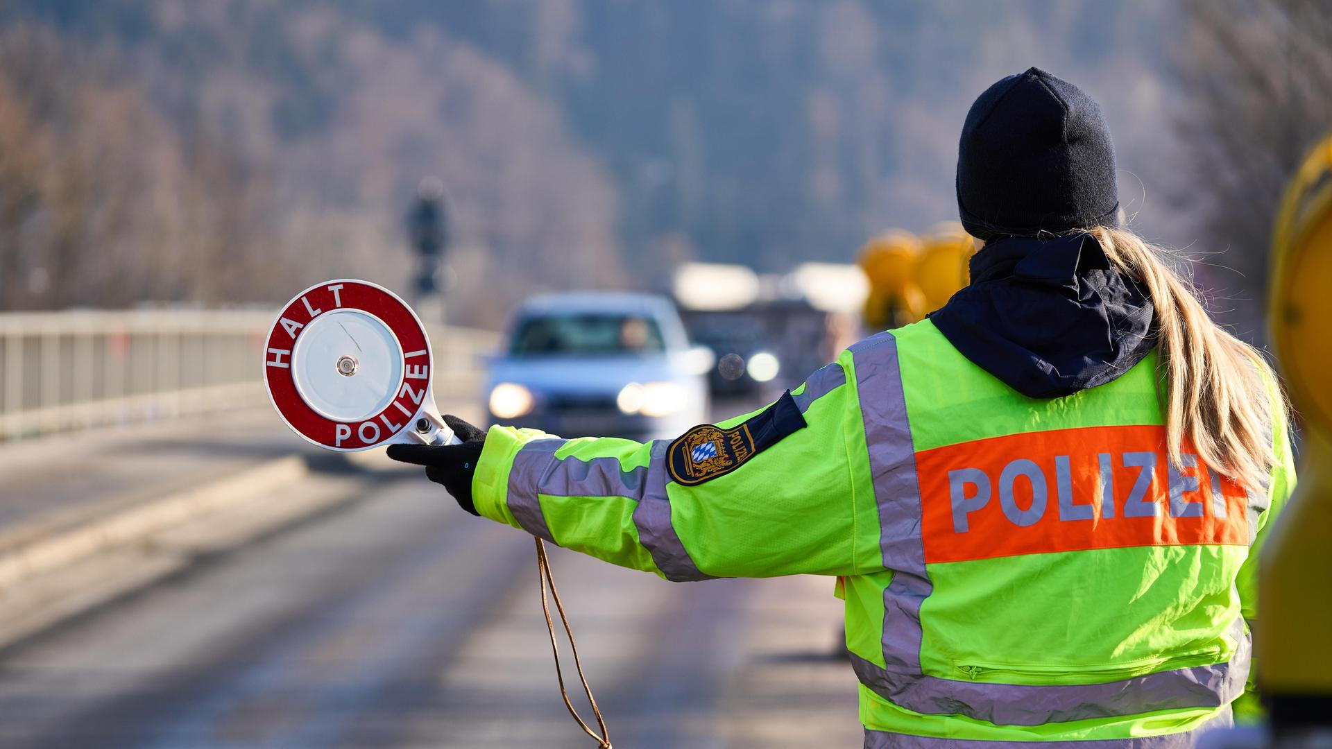 Polizistin stoppt Autoverkehr mit einer Polizeikelle am Grenzübergang