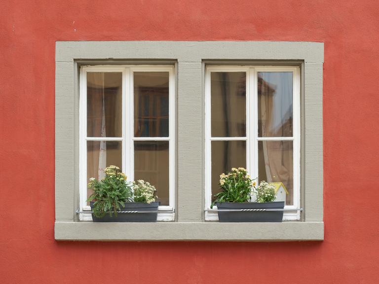 Fenster eines roten Hauses mit Blumen auf dem Fensterbrett