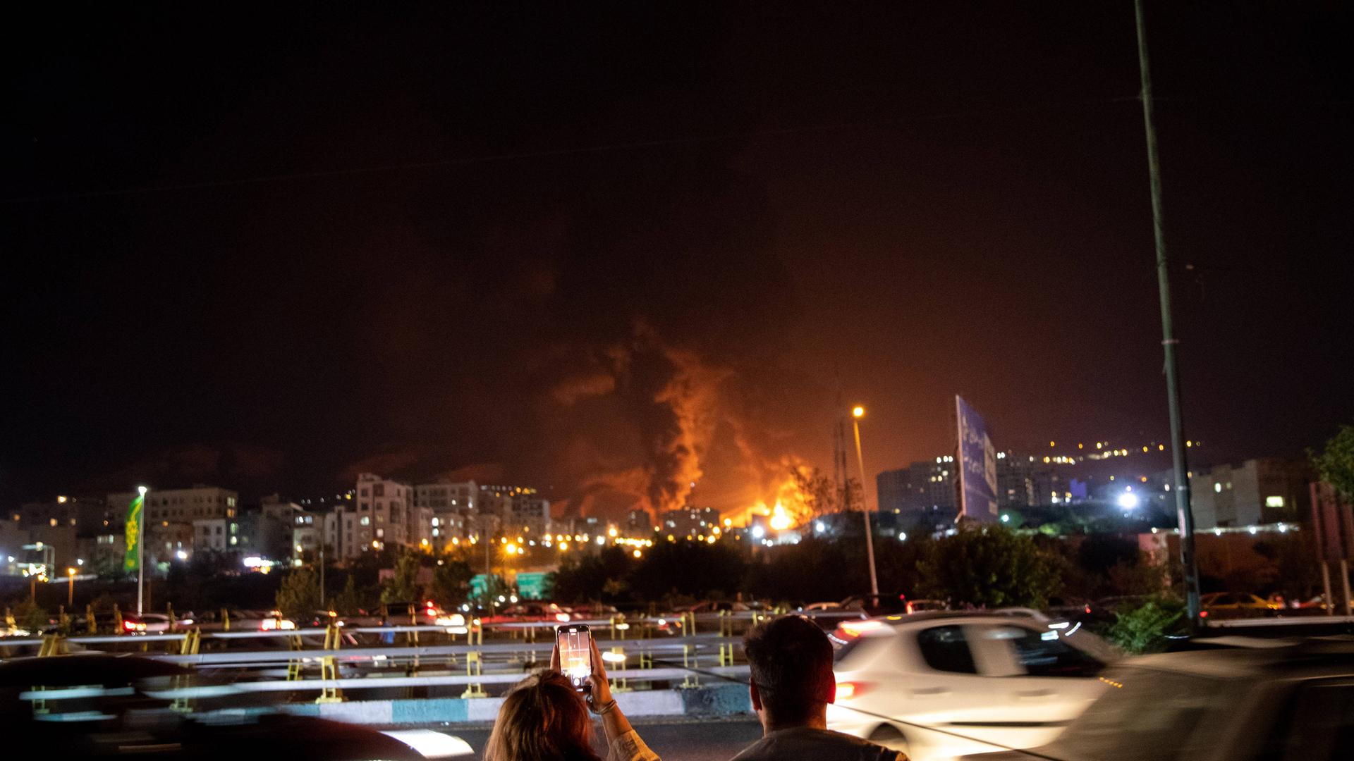 Iraner*innen beobachten am Sonntag, den 15.06.2025 die iranische Hauptstadt Teheran während eines israelischen Luftangriffs