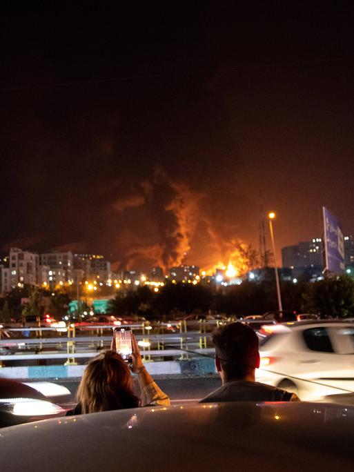 Iraner*innen beobachten am Sonntag, den 15.06.2025 die iranische Hauptstadt Teheran während eines israelischen Luftangriffs