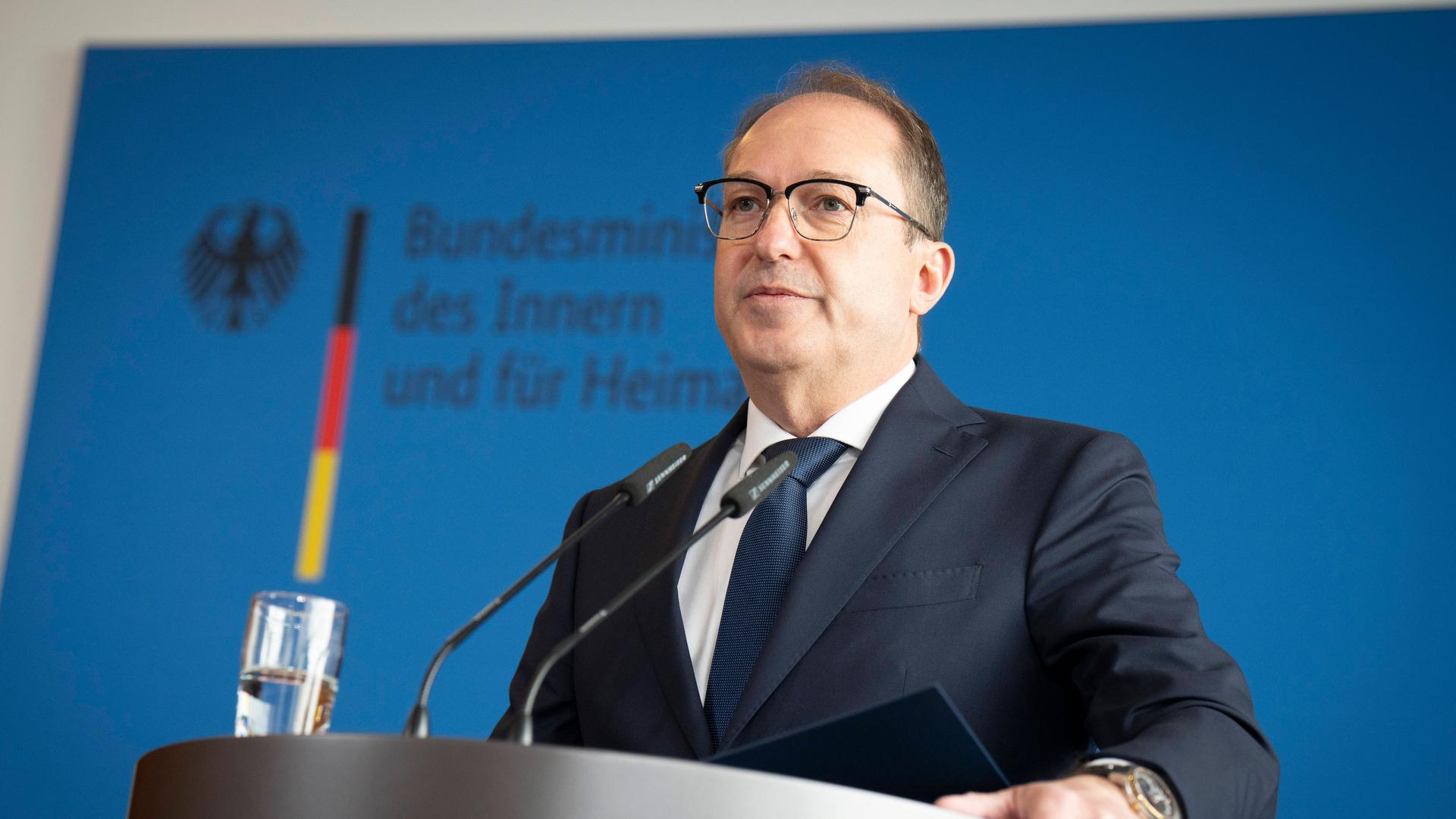 Bundesinnenminister Dobrindt steht bei einer Pressekonferenz an einem Rednerpult. Im Hintergrund ein Plakat mit dem Logo des Bundesinnenministeriums. 