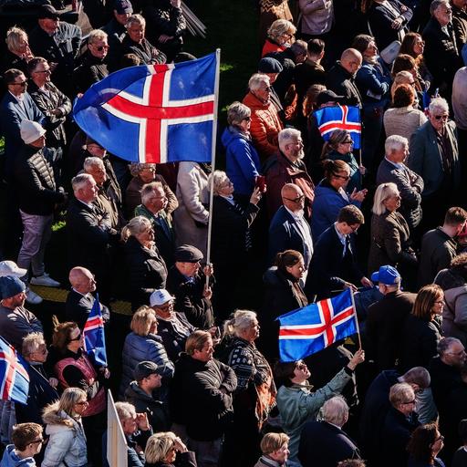 In Islands Hauptstadt Reykjavík stehen viele Menschen bei einer Kundgebung zusammen. Manche haben Island-Flaggen bei sich.