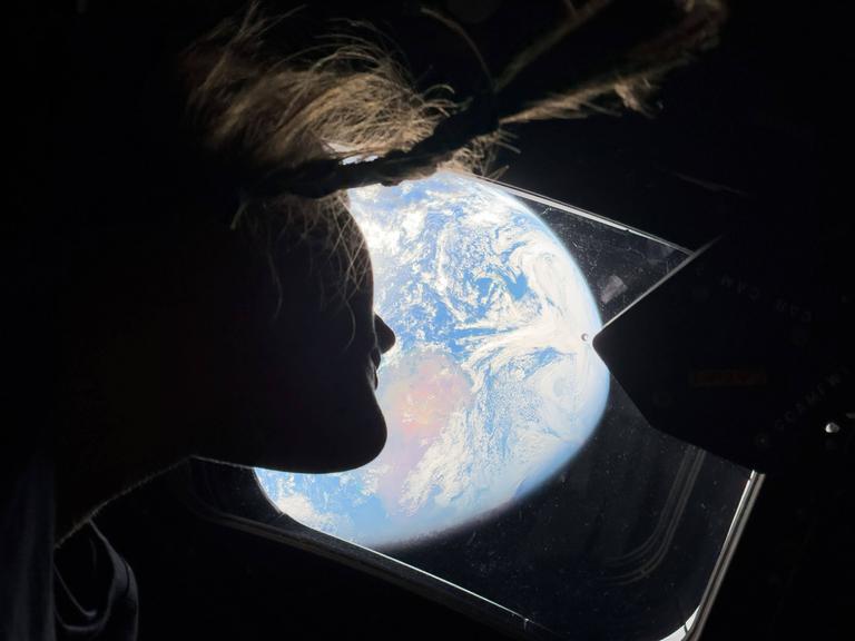Orion-Kapsel, Weltraum: NASA-Astronautin Christina Koch blickt aus einem der Hauptkabinenfenster der Orion-Kapsel zurück zur Erde, während die Besatzung auf dem Weg zum Mond ist.