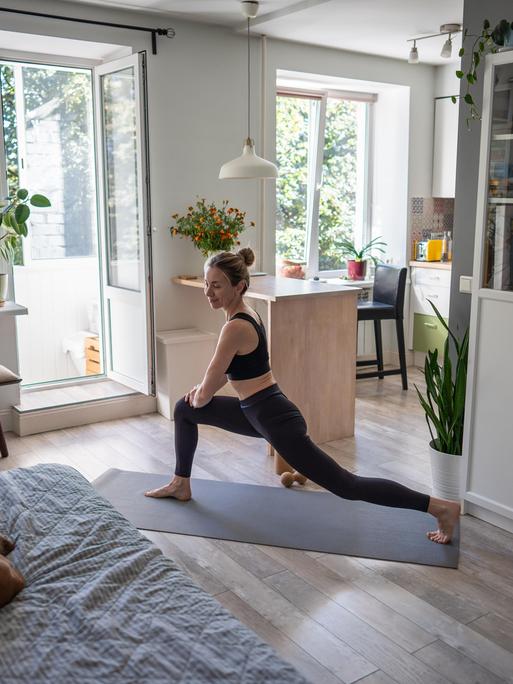 Eine junge Frau macht Yoga-Ausfallschritte als Kraft- und Flexibilitätstraining.