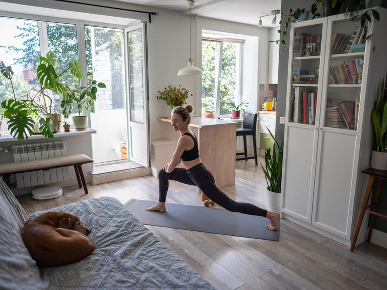 Eine junge Frau macht Yoga-Ausfallschritte als Kraft- und Flexibilitätstraining.