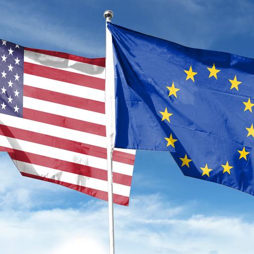 Foto der Flaggen der EU und der USA, die nebeneinander vor blauem Himmel im Wind flattern