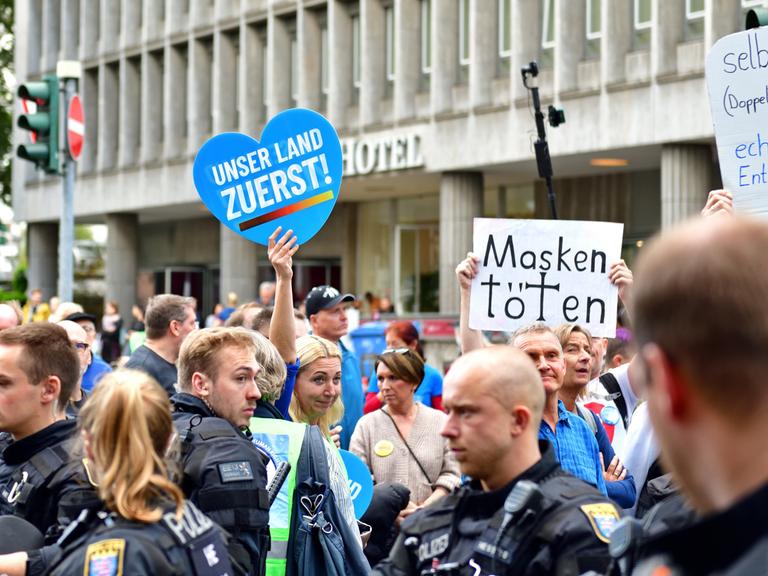 Foto einer Querdenker-Demo in Frankfurt am Main am 22.10.2022, bei der Schilder mit der Aufschrift "Deutschland zuerst!" und "Masken töten" hochgehalten werden.